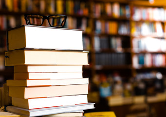 glasses on top of different books lying on table in school library