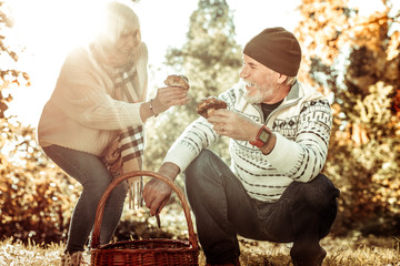 Smiling husband and wife gathering mushrooms together.