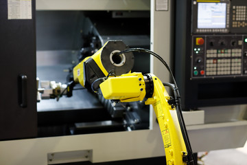 robot arm is loading detail into CNC lathe machine
