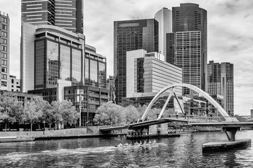 Beautiful black and white view of the Yarra River while a team of athletes rowing in the center of...