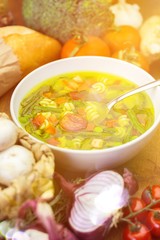 Vegetable soup close-up with ingredients on a wooden table in the sunlight