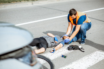 Road accident with injured cyclist on the pedestrian crossing with passerby pedestrian providing...