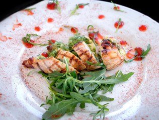 salad with chicken and arugula on a white plate in a cozy restaurant