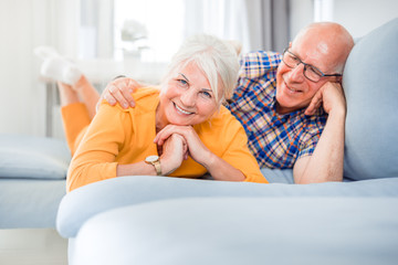 Portrait of cheerful senior couple relaxing and lying on sofa at home