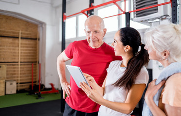 Personal trainer showing results of training on tablet to senior couple