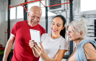 Personal trainer showing results of training on tablet to senior couple
