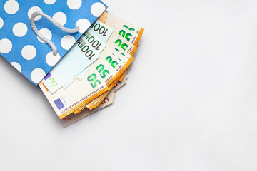 Isolated 100 and 50, hundred and fifty, euros banknotes bills are coming out of a blue paper bag on white background. Shopping sales concept. Copy space place for text