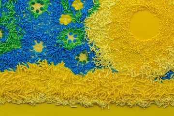 Abstract cake topping sprinkle background with conceptual picture consisting of yellow, blue and green sprinkles close up - top view