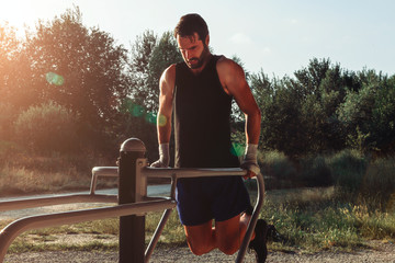 boxer athlete in outdoor training doing pushups at the dip station. sport, healthy life and strength concept