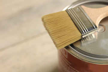 A paint brush lies on a metal can on an old white vintage wooden plank table. Place for text or...
