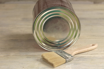 Obraz premium A paint brush is next to a metal can on an old white vintage wooden plank table. Place for text or logo.