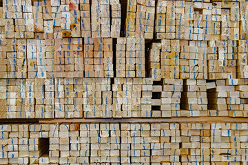 Stacked wooden bars fence on a lumber yard. Building materials.