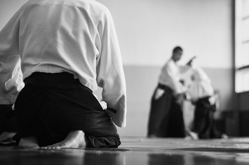 Aikido training. Black and white image. The teacher shows reception.  Traditional form of clothing in Aikido. - obrazy, fototapety, plakaty