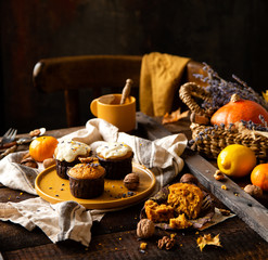 homemade tasty sweet orange pumpkin muffins or cupcakes with white cream, lavender, zest, nuts
