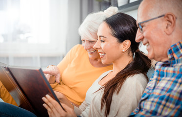 Happy senior parents with their daughter looking at photos in family album