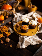 homemade tasty sweet orange pumpkin muffins or cupcakes with white cream, lavender, zest, nuts