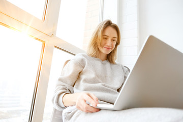 Smiling woman working on laptop in pyjamas