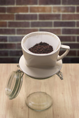 cup of drip coffee with paper filter tool on wood table and brick wall