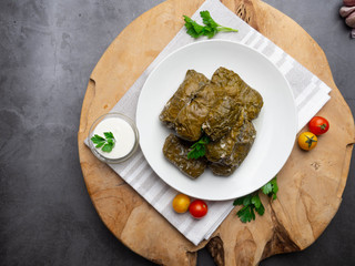 Delicious dolma sarma stuffed grape leaves rice, white yogurt sauce. Lebanese dolma sarma on plate. Lebanon turkish greek middle eastern cuisine. Dinner food dolmadakia or dolma. Yaprak sarma