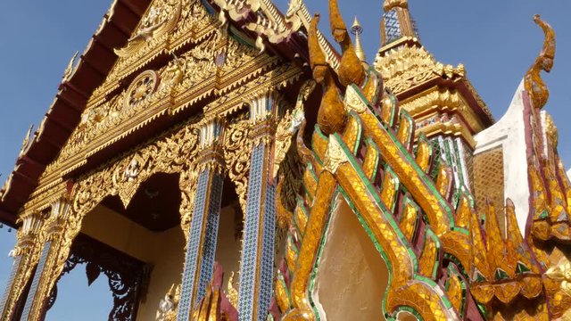 Ornamental roof of oriental temple. Golden ornamental roof of traditional Asian temple against cloudless blue sky on sunny day. Wat Plai Laem. Koh Samui