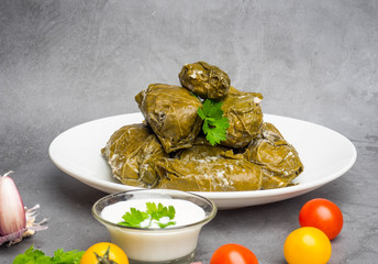 Delicious dolma sarma stuffed grape leaves rice, white yogurt sauce. Lebanese dolma sarma on plate. Lebanon turkish greek middle eastern cuisine. Dinner food dolmadakia or dolma. Yaprak sarma