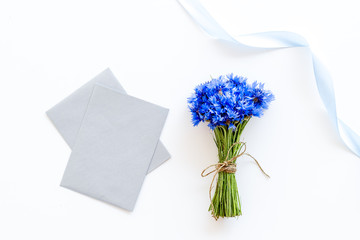 Field flowers design with bouquet of blue cornflowers and envelopes for present on white background top view mock-up