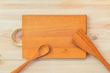 Food background. Top view of empty wooden cutting board, spoon and spatula on planks vintage table with copy space.
