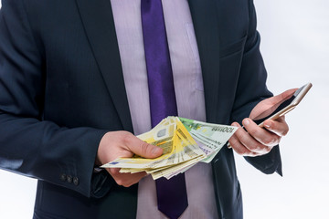 Businessman holds in one hand euro and another phone