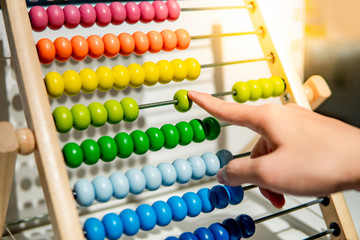 Male hand calculating with beads on wooden rainbow abacus for number calculation. Mathematics learning concept