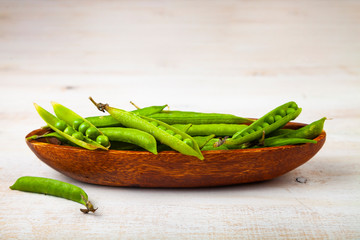 Green peas in a wooden bowl.