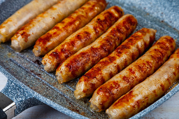 Kupaty in a frying pan on a wooden table.