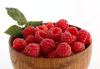 Bright, juicy berries of a garden raspberry with a green leaf in a wooden cup on a white background. Isolated. Close-up.