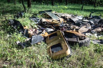 A pile of garbage auto parts in the forest.