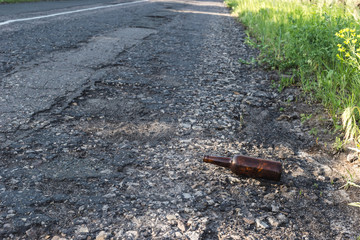 Brown beer bottle by the road.