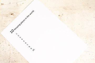 White sheet of paper with the inscription ten amazing places in the world . Light background. Travel planning.