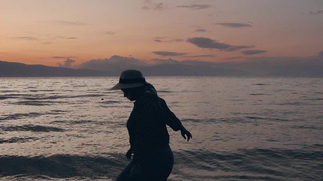 Dolly shot of a girl walking on the beach at sunset 4k