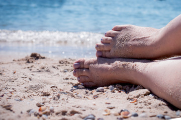 feet on the sand against the blue sea