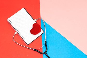 Stethoscope and notebook and red heart ,cardiogram on blue background. Cardiology concept