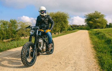 Fototapeta na wymiar Young man with helmet riding a custom motorbike outdoors