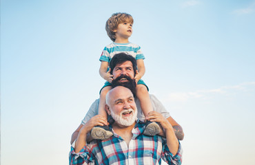 Men generation: grandfather father and grandson are hugging looking at camera and smiling. Fathers day concept. Generation concept. Weekend family play. Men in different ages. - obrazy, fototapety, plakaty