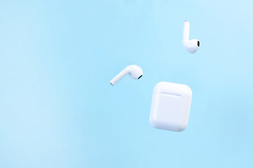 Wireless white headphones with a case on a blue background.