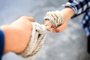 Two hands one wearing a blue shirt and black tie while the other wearing black and white square...