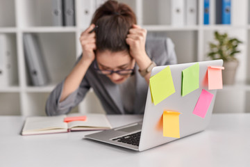 Laptop near stressed woman in office