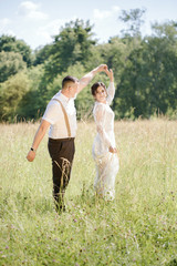 Naklejka na ściany i meble Newlywed couple dancing in the meadow