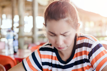 Obraz premium A beautiful Asian woman is making a stressful face while looking at the smartphone.
