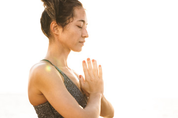 Photo of concentrated fitness woman meditating and keeping palms together while practicing yoga in morning outdoors