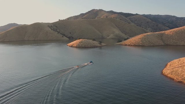 Aerial Drone Tracking Shot of a Boat Towing a Tube on.a Mountain Lake (Lake Kaweah, Visalia, California)