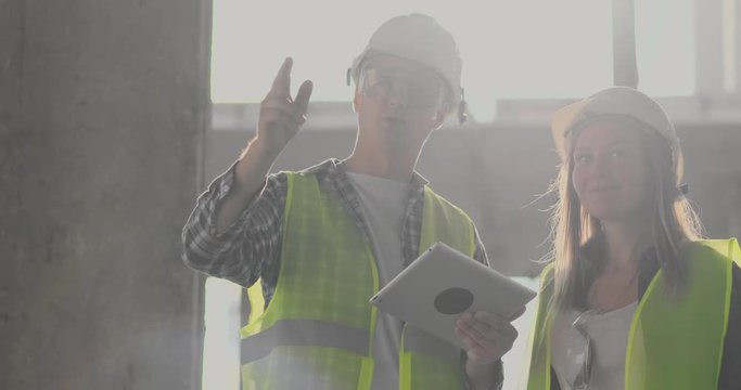 Engineers or architects have a discussion at construction site looking through the plan of construction. contre jour. Engineers or architects have a discussion.