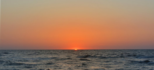 Obraz premium The sun sets in the sea on a clear evening