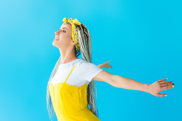 happy girl with dreadlocks with outstretched hands posing isolated on turquoise
